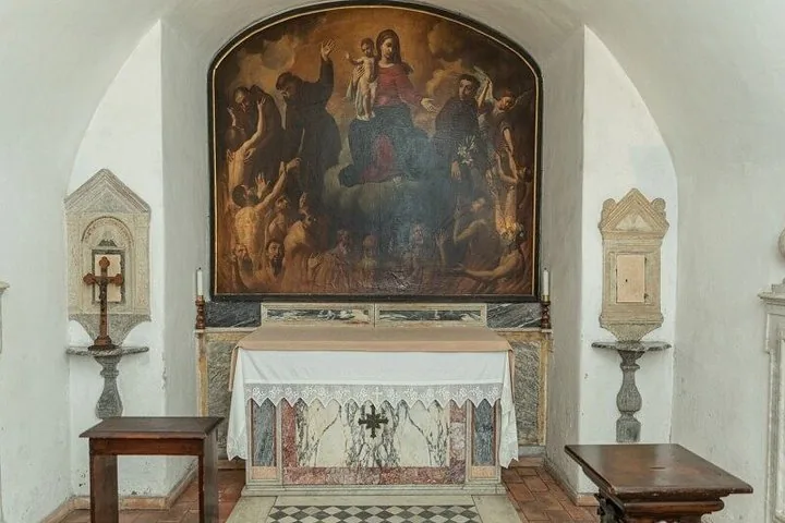 A small altar inside an alcove with a religious painting and decorative stone elements.