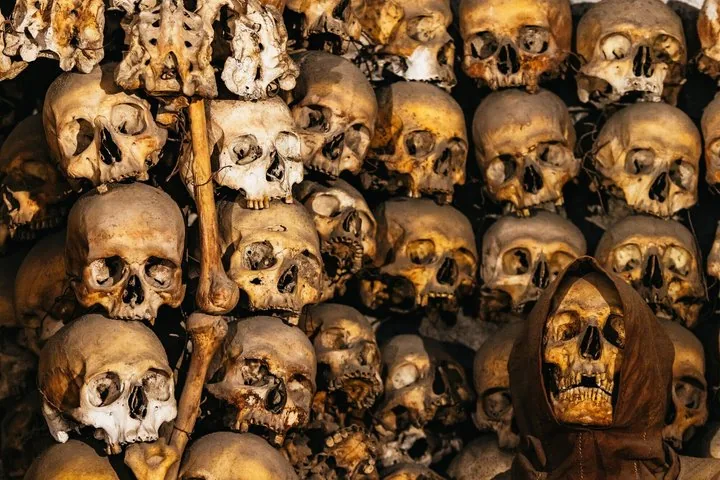A dense stack of human skulls and bones forming a macabre wall display.