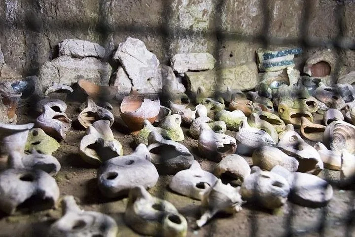 Ancient broken pottery and artifacts displayed behind a wire mesh fence.